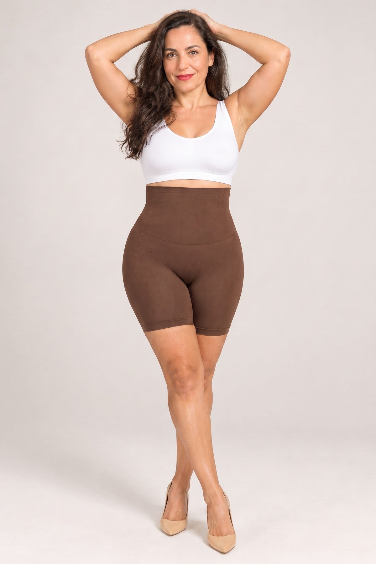 Seamless High-Waist Shaping Shorts in Brown, arms raised, worn with a white top