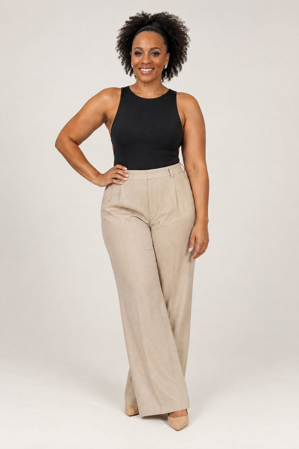 Woman in a fitted black open-back top and oat wide-leg trousers, front