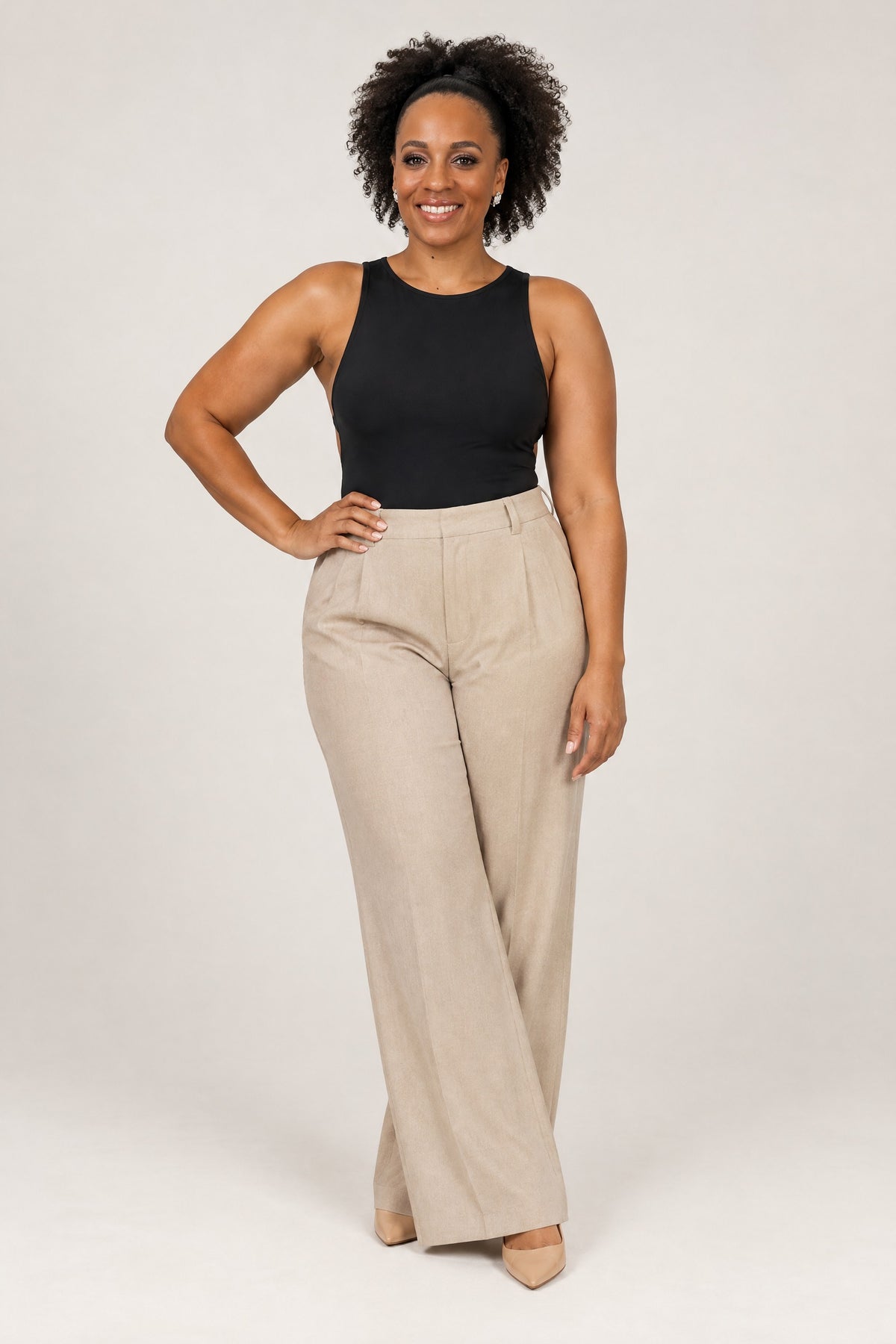 Woman in a fitted black open-back top and oat wide-leg trousers, front